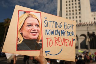 A person holds a sign with a photo of US Attorney General Pam Bondi and featuring a quote in reference to the Epstein files last Thursday